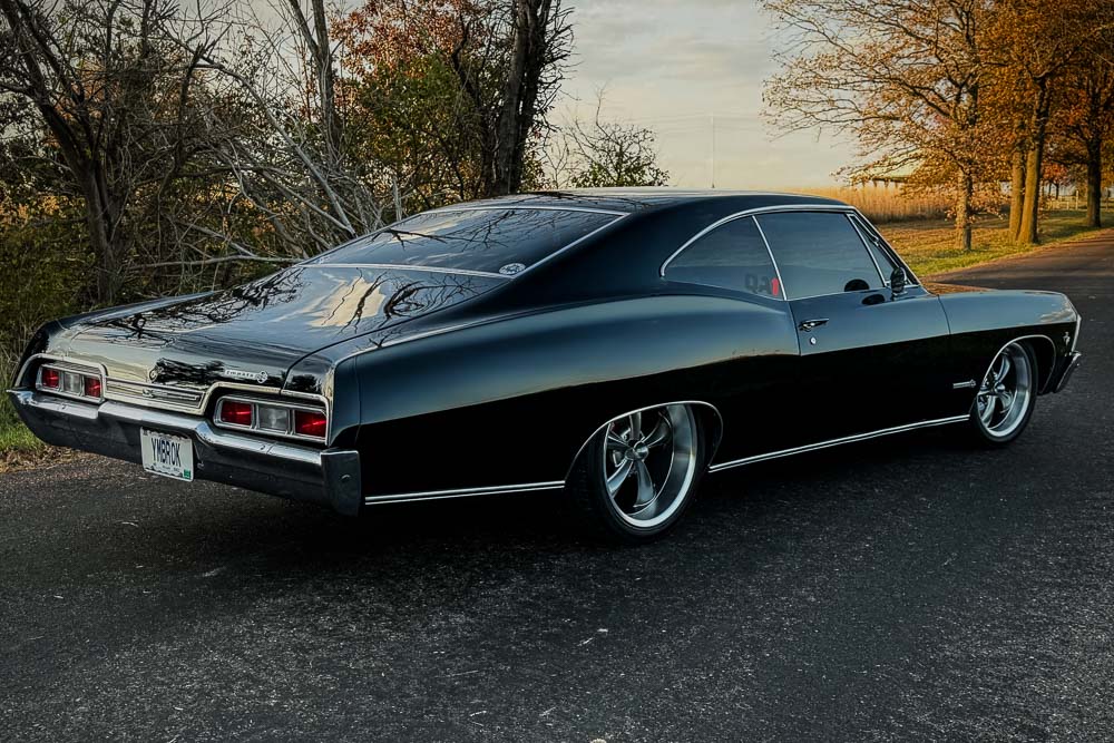 Custom black Spies Hecker paint job on the 1967 Impala SS, glowing under sunlight.